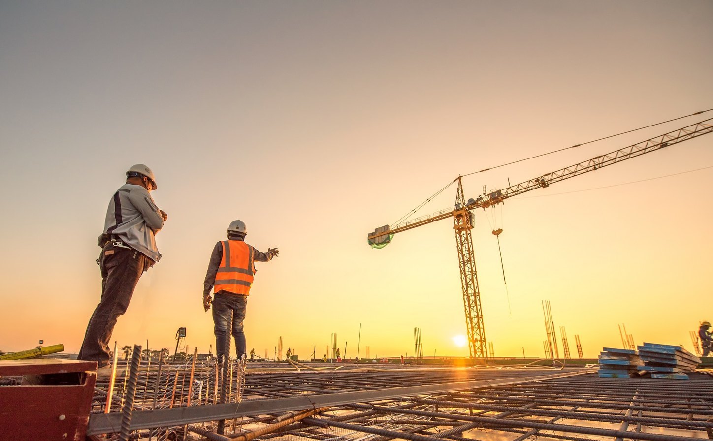 Two workers on the roof of a building under construction beside a crane, before a lifeline inspection